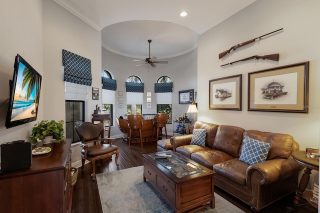 living area featuring baseboards, a ceiling fan, dark wood-type flooring, and crown molding