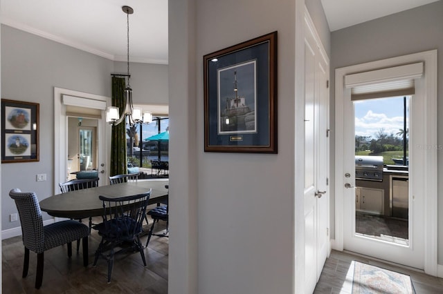 dining area featuring ornamental molding, an inviting chandelier, wood finished floors, and baseboards