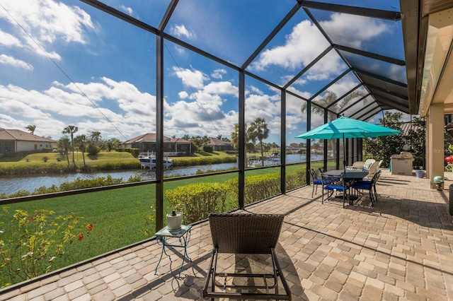 view of patio / terrace with outdoor dining space, a water view, and a lanai