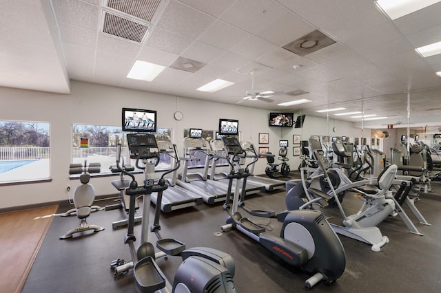 exercise room featuring a ceiling fan, a paneled ceiling, visible vents, and baseboards