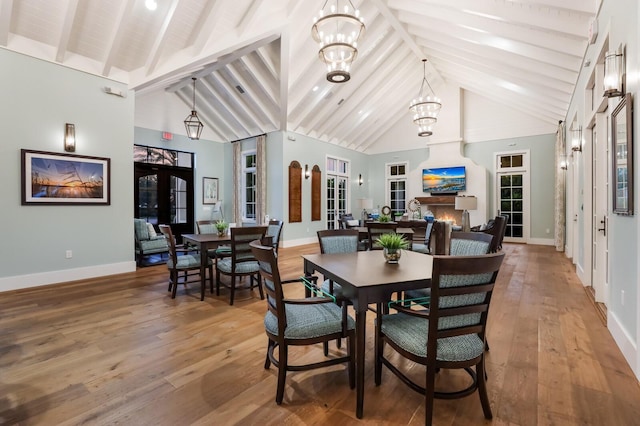 dining area featuring a chandelier, french doors, wood-type flooring, and beam ceiling