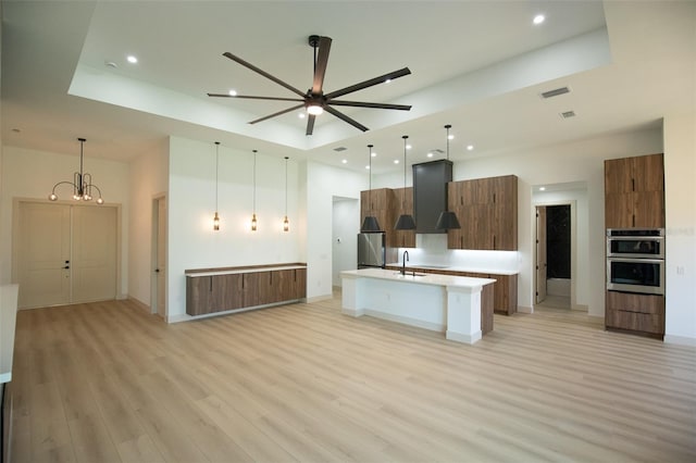 kitchen with visible vents, a tray ceiling, open floor plan, and a sink