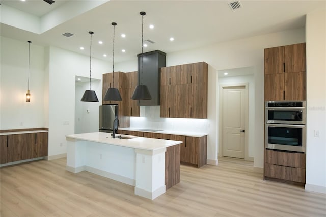 kitchen featuring stainless steel appliances, a kitchen island with sink, visible vents, and modern cabinets