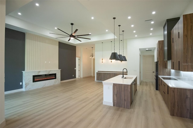 kitchen featuring a spacious island, light wood-style flooring, modern cabinets, and a fireplace