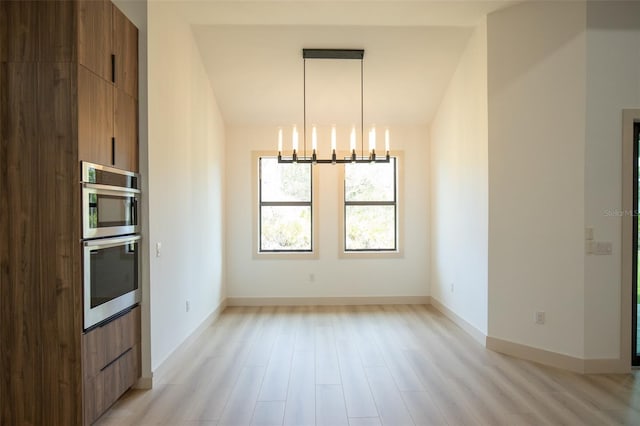 unfurnished dining area featuring light wood-type flooring, vaulted ceiling, and a notable chandelier