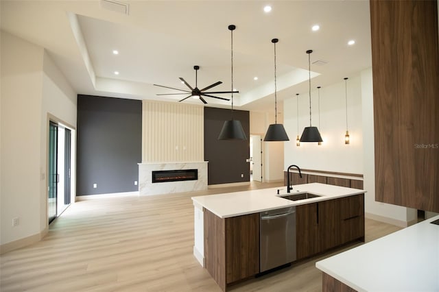 kitchen featuring modern cabinets, a tray ceiling, stainless steel dishwasher, and a high end fireplace