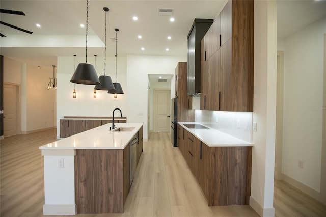 kitchen with a spacious island, light wood-style flooring, modern cabinets, black appliances, and a sink