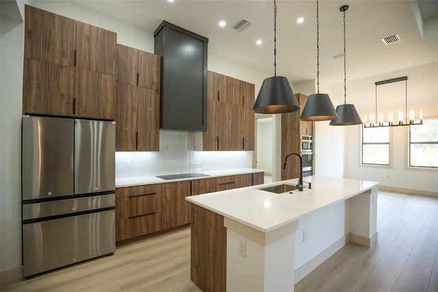 kitchen featuring modern cabinets, black electric stovetop, a sink, and freestanding refrigerator