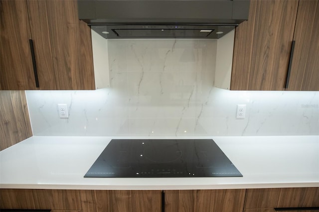 room details featuring brown cabinetry, backsplash, black electric stovetop, and modern cabinets