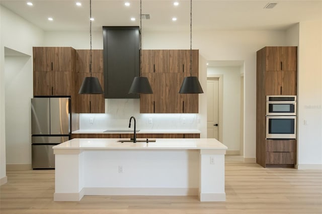 kitchen featuring an island with sink, modern cabinets, appliances with stainless steel finishes, and light countertops