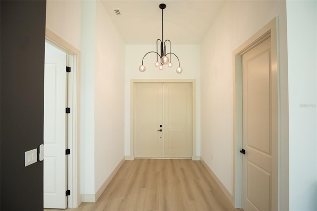 interior space with visible vents, a notable chandelier, light wood-style flooring, and baseboards