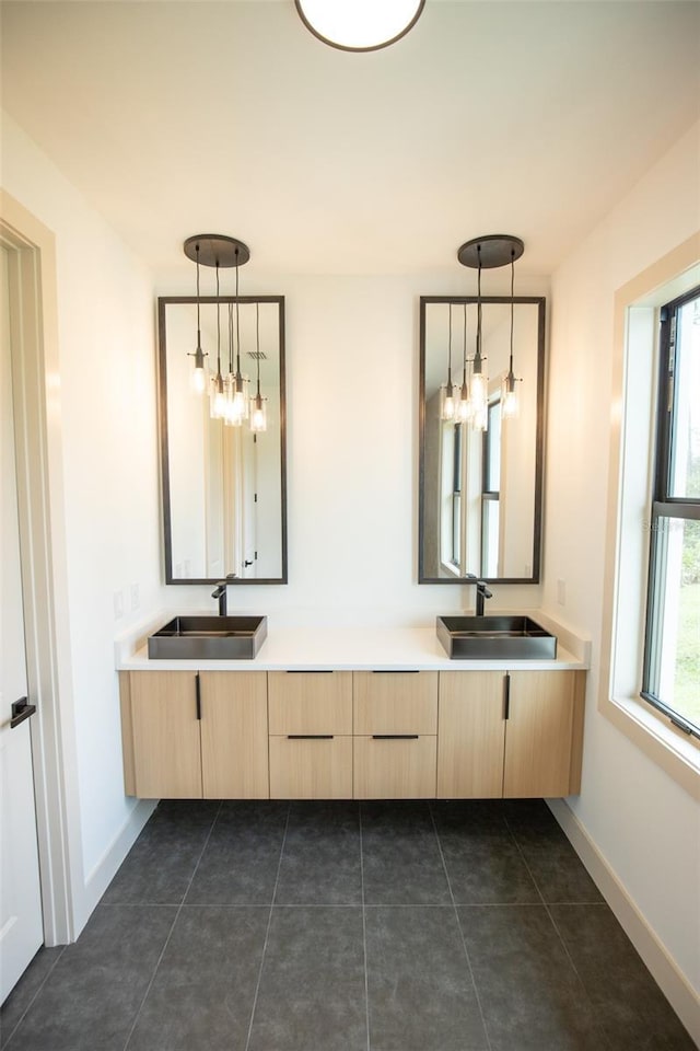 bathroom with double vanity, a sink, and baseboards