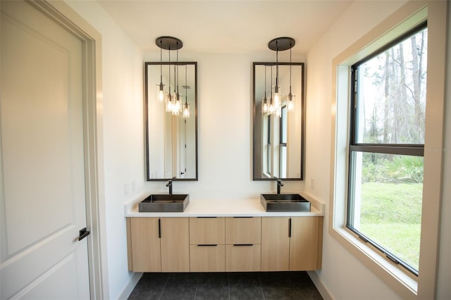 full bathroom featuring baseboards, double vanity, a sink, and tile patterned floors