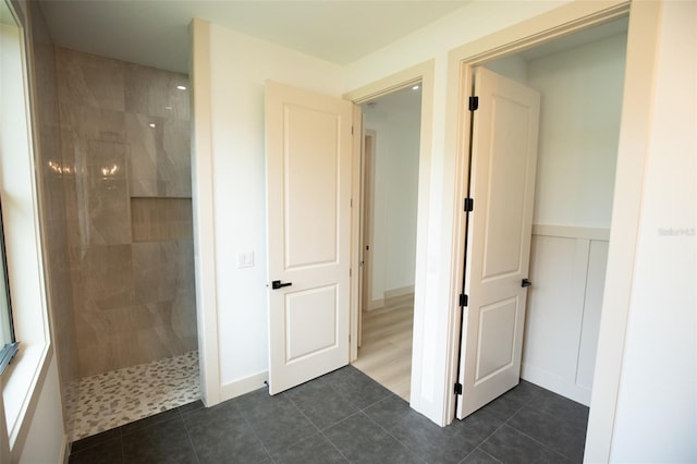 bathroom featuring a decorative wall, wainscoting, walk in shower, and tile patterned floors