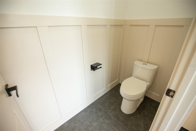 bathroom featuring a decorative wall, toilet, and tile patterned floors