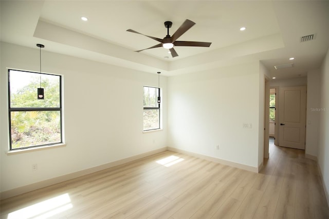 empty room with visible vents, a raised ceiling, and a wealth of natural light