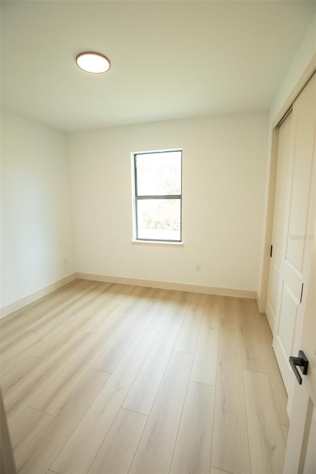 unfurnished bedroom with light wood-style floors, a closet, and baseboards