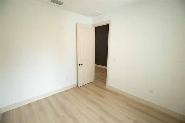 unfurnished room with light wood finished floors, baseboards, and visible vents