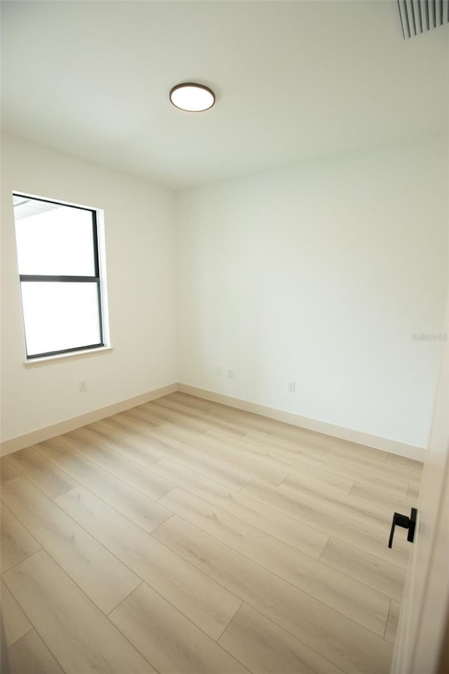 unfurnished room featuring light wood-style flooring, visible vents, and baseboards