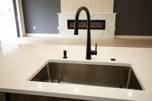 room details featuring a sink, light countertops, a glass covered fireplace, and baseboards