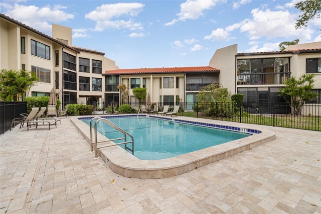 community pool with fence and a patio