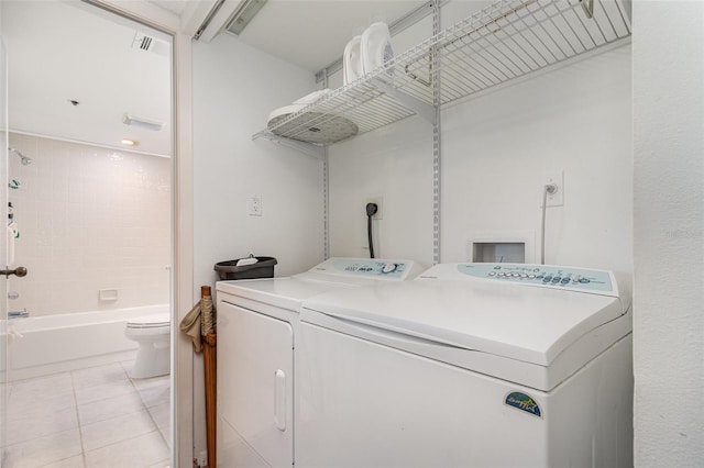 laundry room featuring light tile patterned floors, visible vents, washing machine and clothes dryer, and laundry area