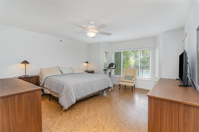 bedroom featuring ceiling fan, light wood-style flooring, and baseboards