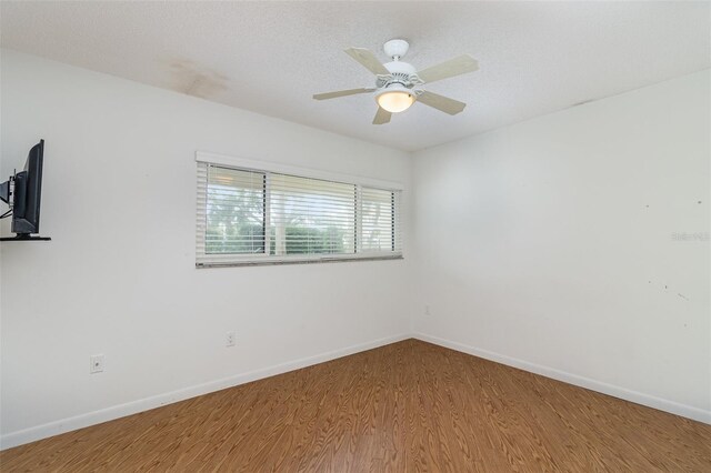 spare room featuring baseboards, wood finished floors, and a ceiling fan