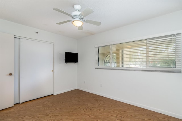 unfurnished bedroom with a closet, ceiling fan, wood finished floors, and baseboards