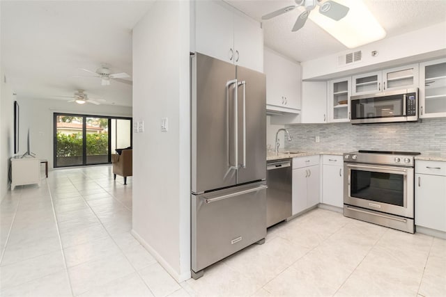 kitchen featuring light tile patterned flooring, a ceiling fan, visible vents, backsplash, and appliances with stainless steel finishes