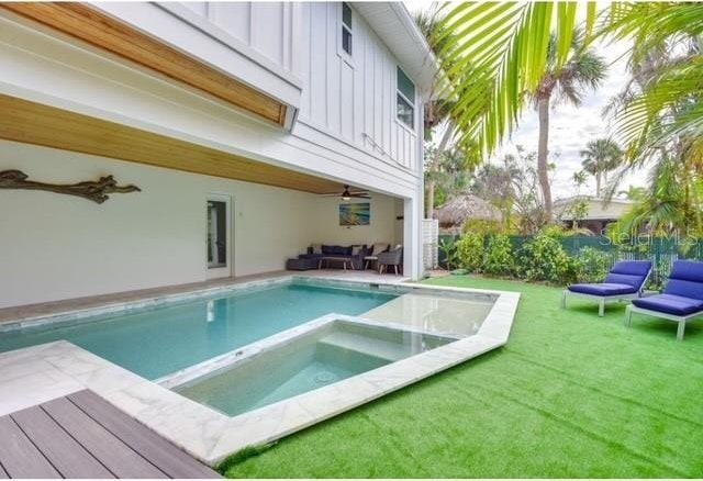 view of pool featuring a yard, ceiling fan, an outdoor living space, and an in ground hot tub