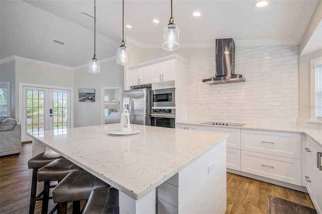 kitchen with crown molding, wall chimney exhaust hood, lofted ceiling, and stainless steel appliances