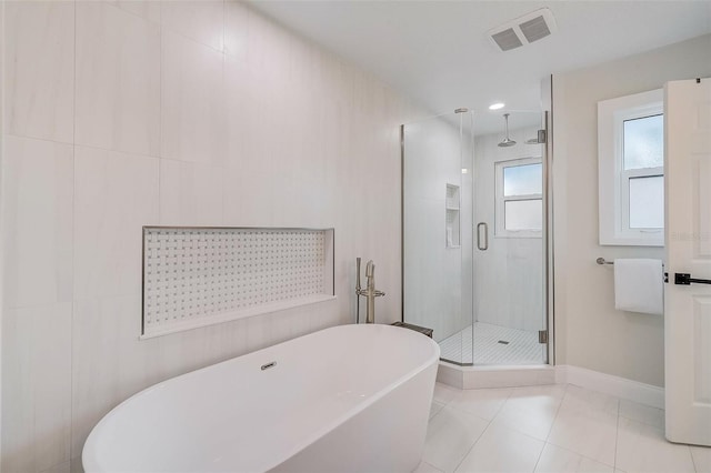 bathroom with a freestanding tub, visible vents, baseboards, tile patterned floors, and a stall shower