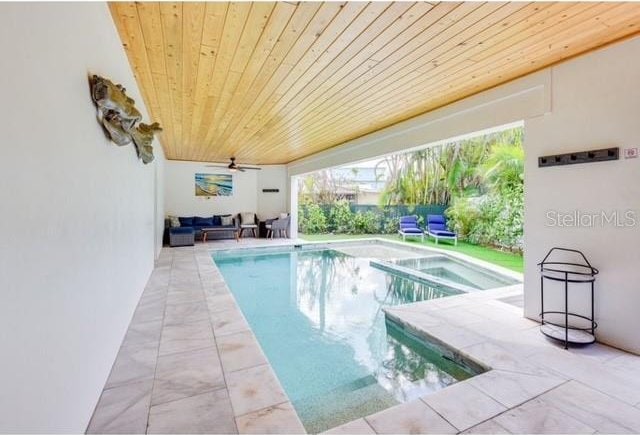 view of swimming pool with outdoor lounge area, a patio area, a pool with connected hot tub, and a ceiling fan