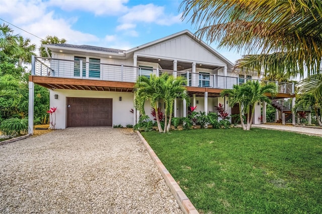 view of front of property featuring an attached garage, a balcony, driveway, stucco siding, and a front yard