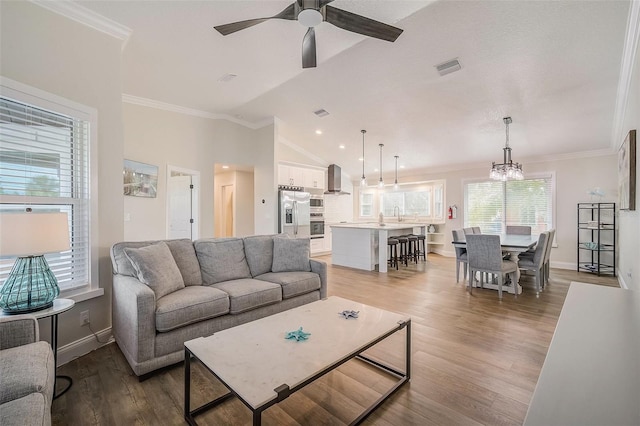 living room featuring lofted ceiling, light wood-style flooring, visible vents, and crown molding