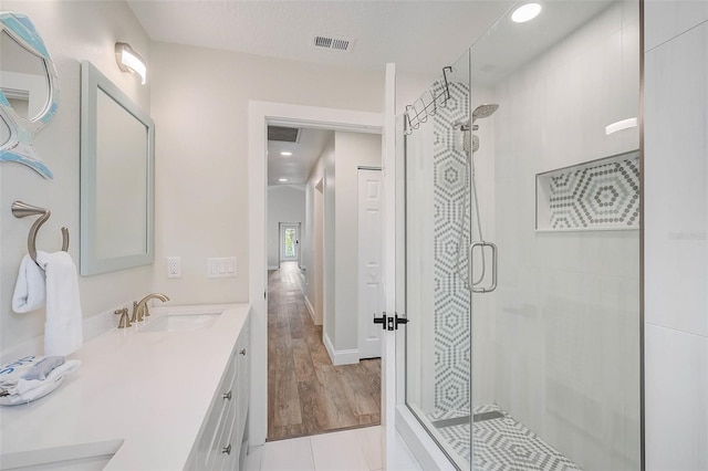 full bath featuring visible vents, a sink, a shower stall, and double vanity