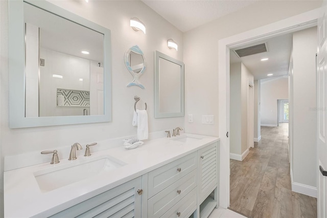 full bathroom featuring double vanity, visible vents, a sink, and wood finished floors