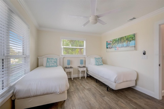 bedroom with ornamental molding, wood finished floors, visible vents, and baseboards