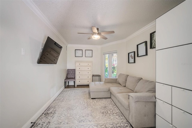 living area featuring a textured ceiling, ceiling fan, wood finished floors, baseboards, and ornamental molding