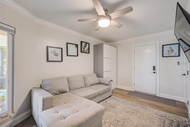 living area featuring ornamental molding, wood finished floors, a ceiling fan, and baseboards