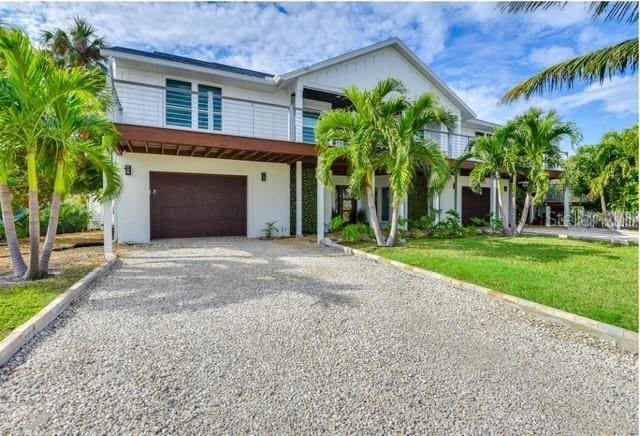 5708 Holmes Blvd, Holmes Beach, FL 34217 - view of front facade with gravel driveway, an attached garage, stucco siding, and a front yard