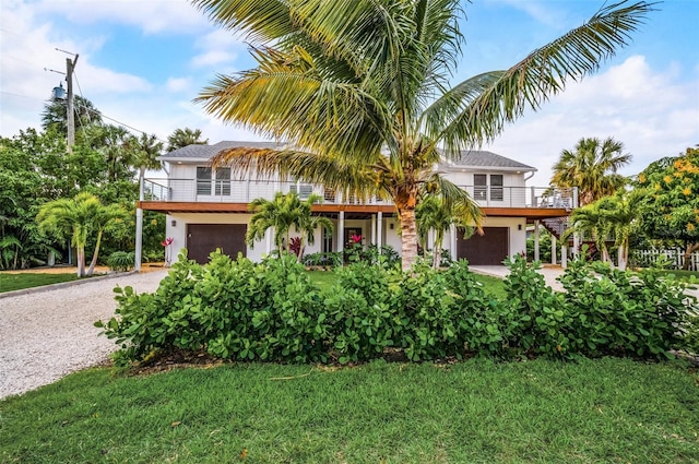 5708 Holmes Blvd, Holmes Beach, FL 34217 - view of front of house with an attached garage, driveway, a balcony, and a front lawn