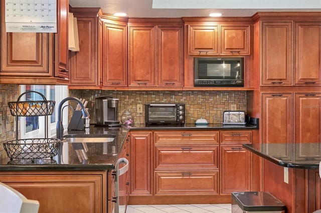 kitchen with black microwave, a sink, brown cabinets, dark stone counters, and tasteful backsplash