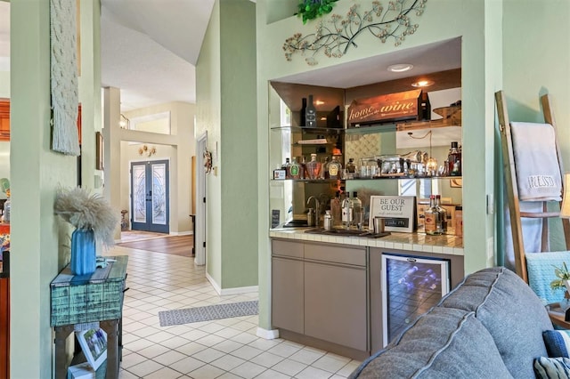 bar with french doors, light tile patterned floors, wet bar, beverage cooler, and baseboards