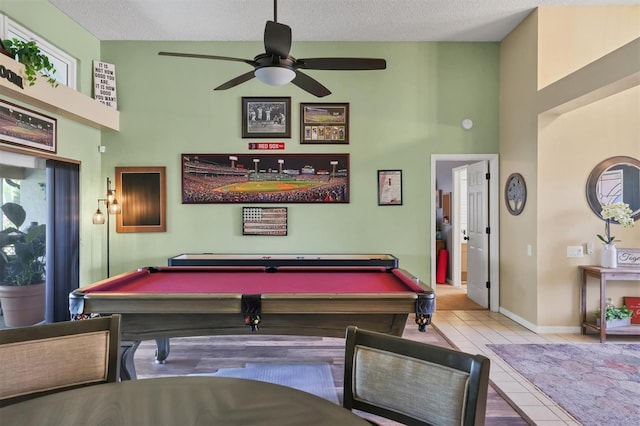 recreation room featuring a textured ceiling, tile patterned flooring, a ceiling fan, and baseboards