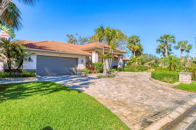 mediterranean / spanish-style house featuring an attached garage, a tiled roof, decorative driveway, stucco siding, and a front yard