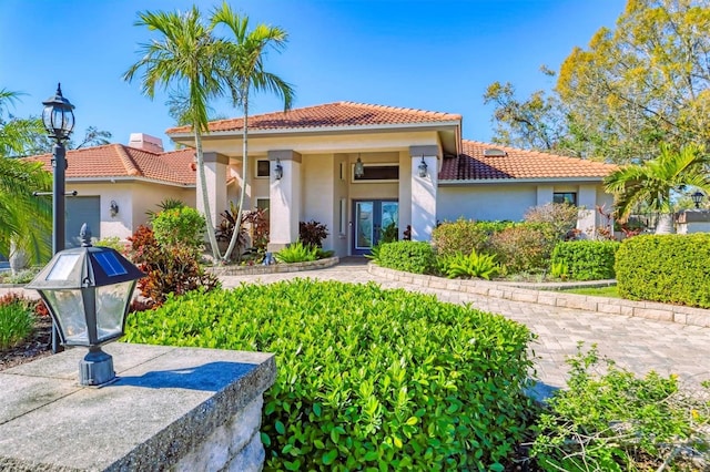 mediterranean / spanish-style home with a garage, french doors, a tile roof, and stucco siding