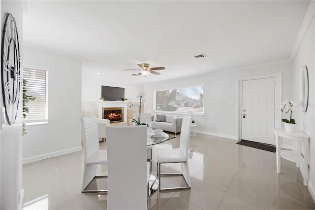 dining space featuring a warm lit fireplace, visible vents, baseboards, and light tile patterned floors