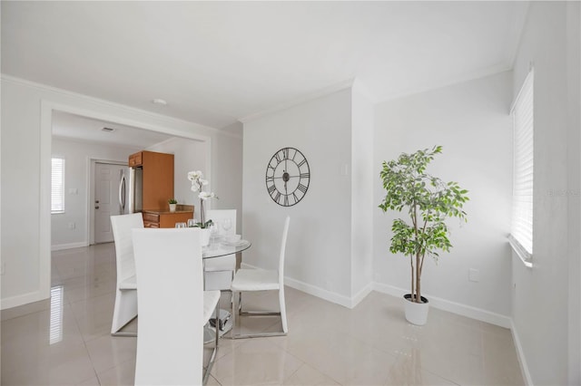 dining room featuring baseboards, light tile patterned floors, and crown molding